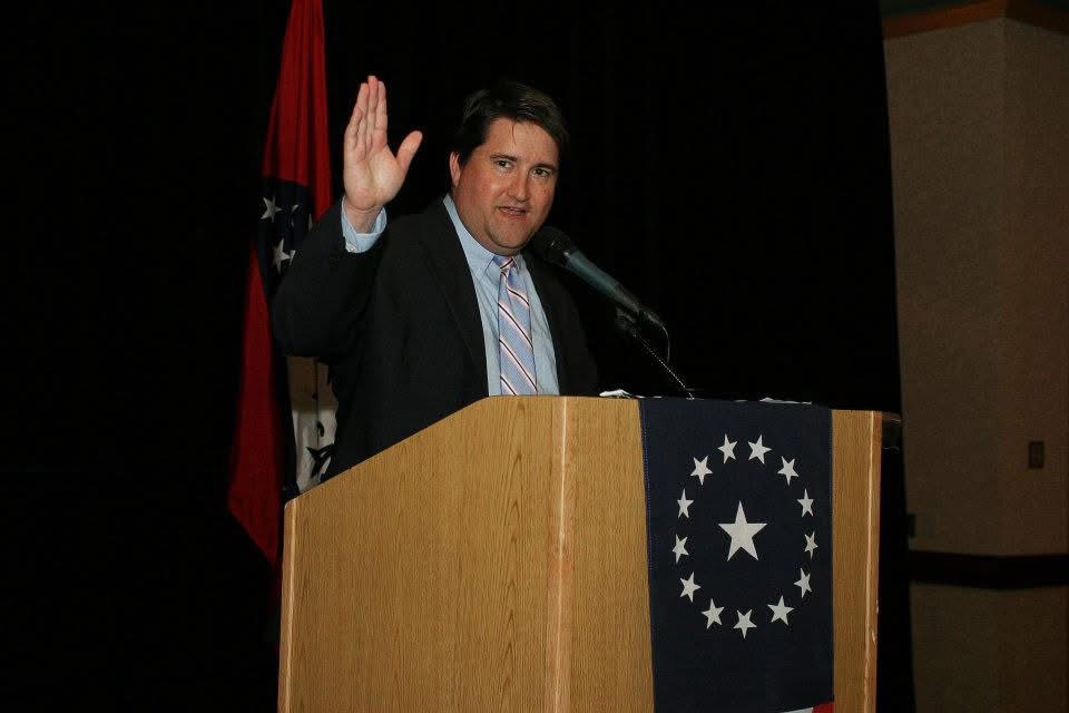 Cory Cox addressing a Republican event in front of the Arkansas state flag